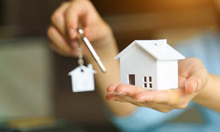 Una mujer sosteniendo las llaves de su nuevo hogar gracias al subsidio de vivienda de colsubsidio.
