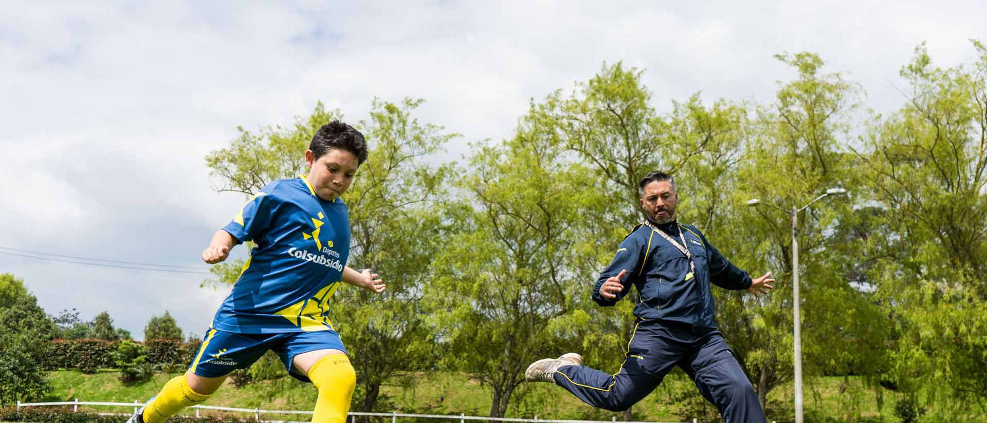 Un niño practicando fútbol con su entrenador deportivo.