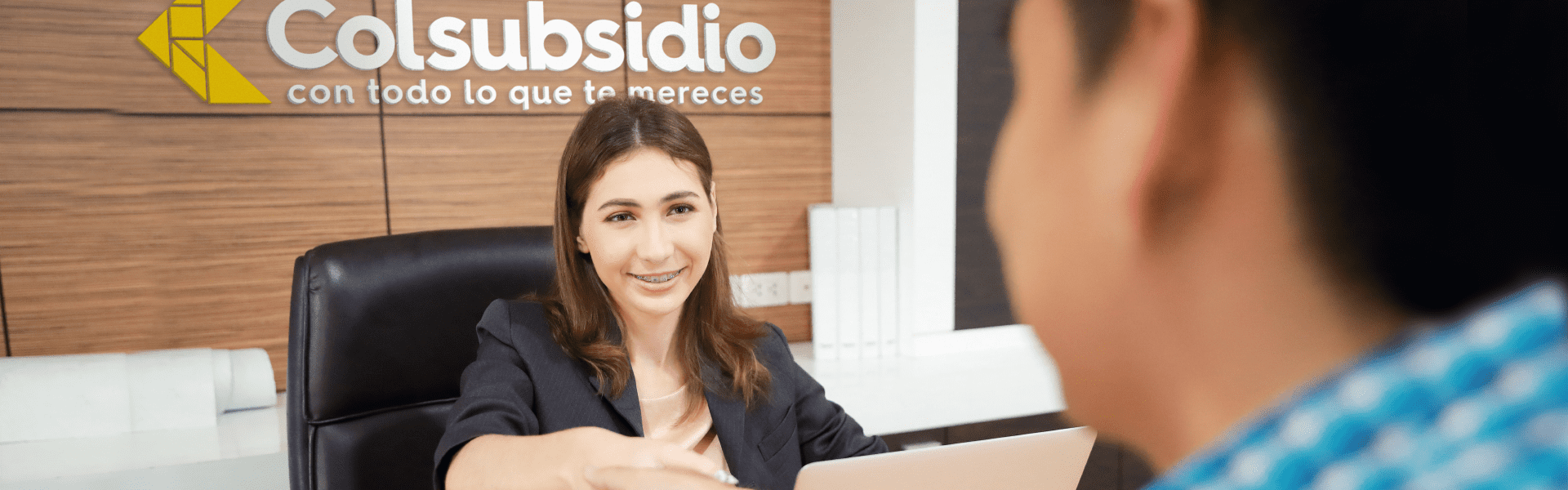 Mujer joven recepcionista brindando atención al cliente en uno de los puntos de crédito Colsubsidio.