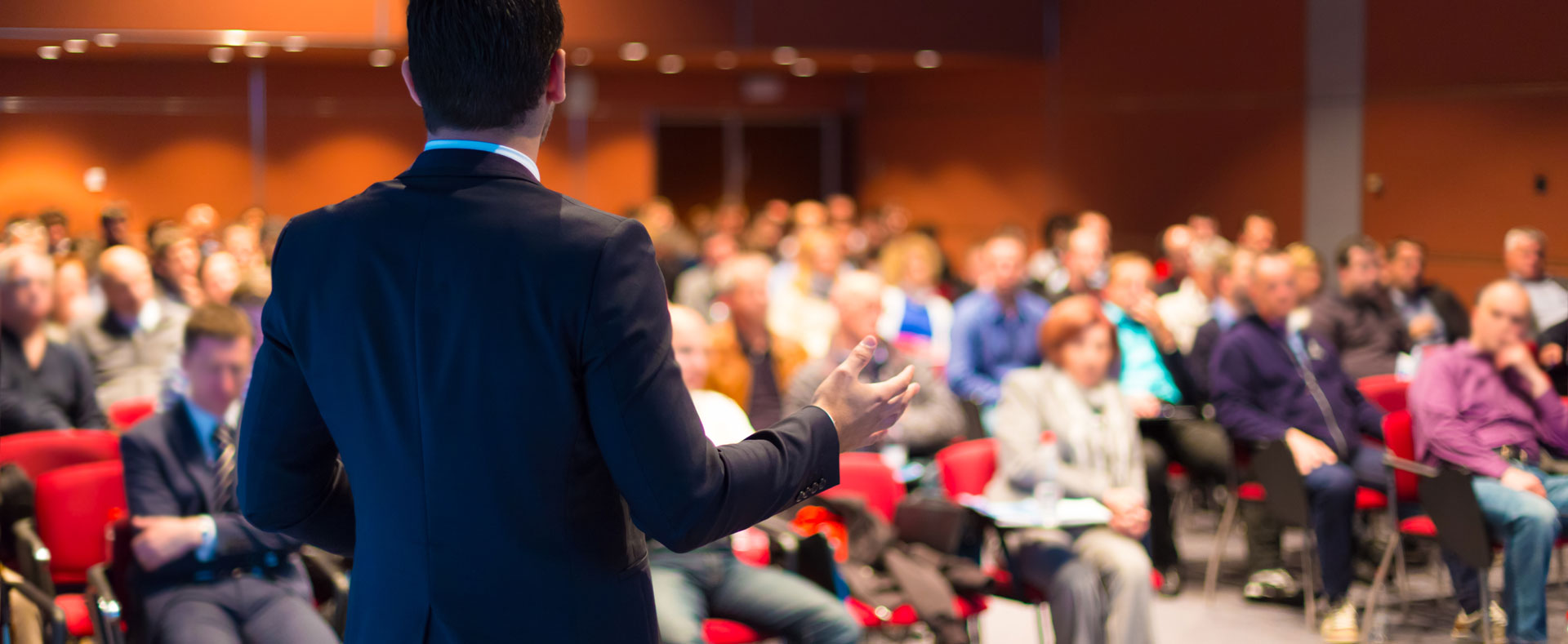 Un conferenciaste, hablando hacia un grupo de personas.