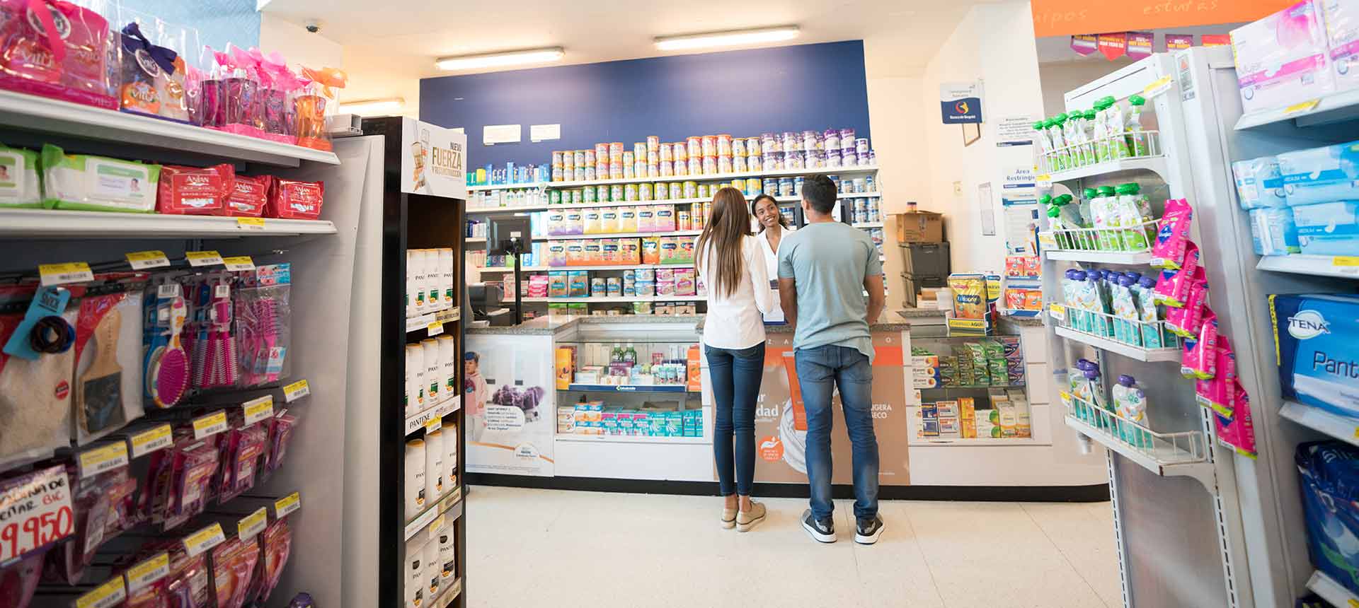 Dos personas siendo atendidas por una farmaceuta de droguerías Colsubsidio.