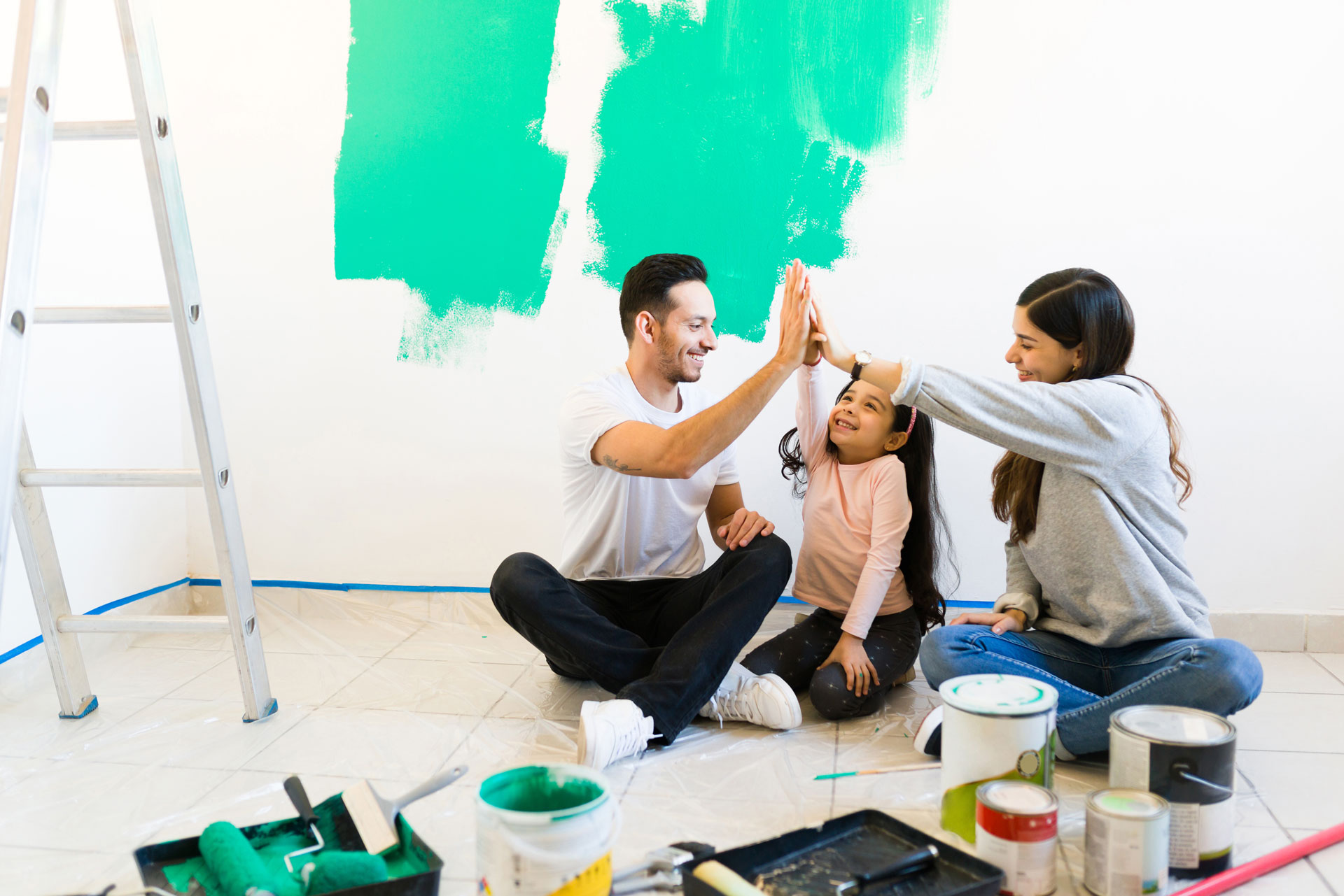 Familia feliz, pintando su nueva casa gracias al subsidio de mejoramiento de vivienda.
