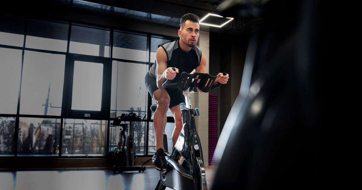 Un hombre, enfocado, entrenando en una bicicleta estática de los Clubes Colsubsidio. 