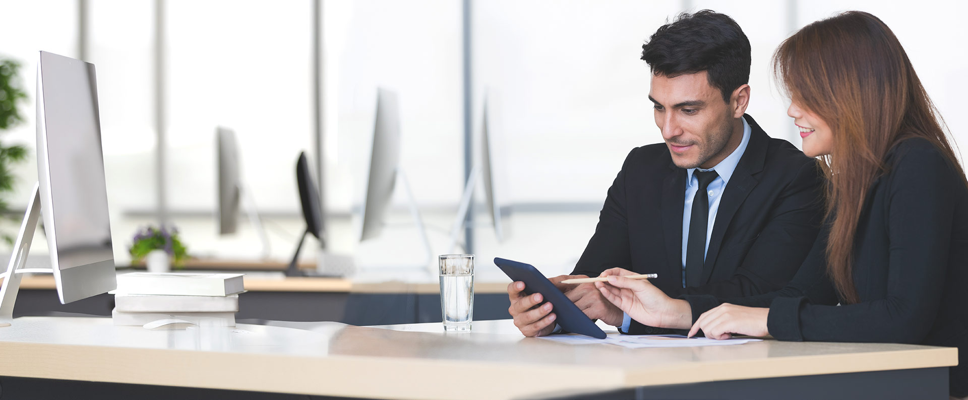 Dos compañeros de trabajo revisando información en su tablet, sentados en su oficina.