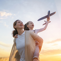 Una madre divirtiéndose con su hija, con un avión de juguete.