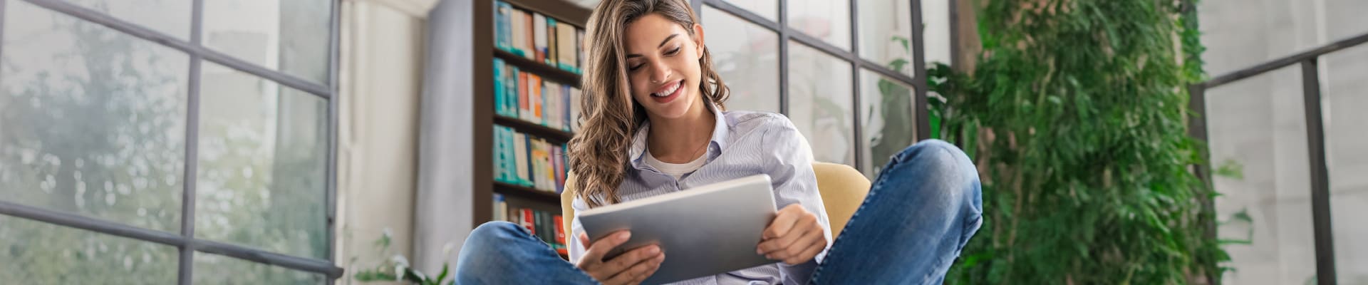 Mujer joven revisando su tablet en la sala de su casa.