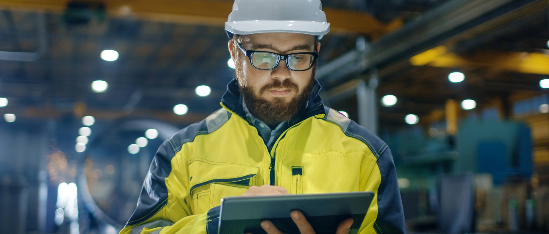 Un hombre ingeniero con casco de protección, revisando información en una tablet.