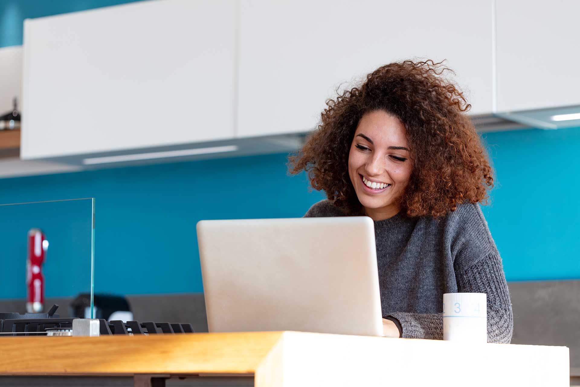 Una mujer sonriendo frente a su computador portátil.