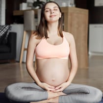 Mujer embarazada sentada en el suelo, cierra los ojos imaginado su bebé.