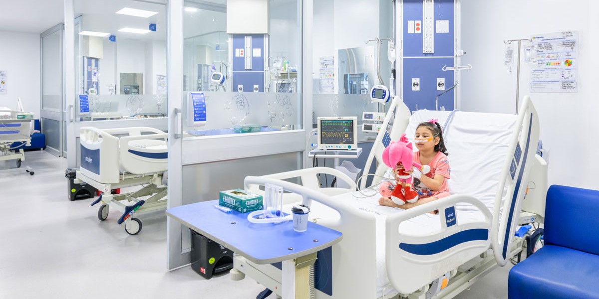 Espacios UCI de la Clínica Infantil Colsubsidio y una paciente en atención respiratoria con su peluche. 