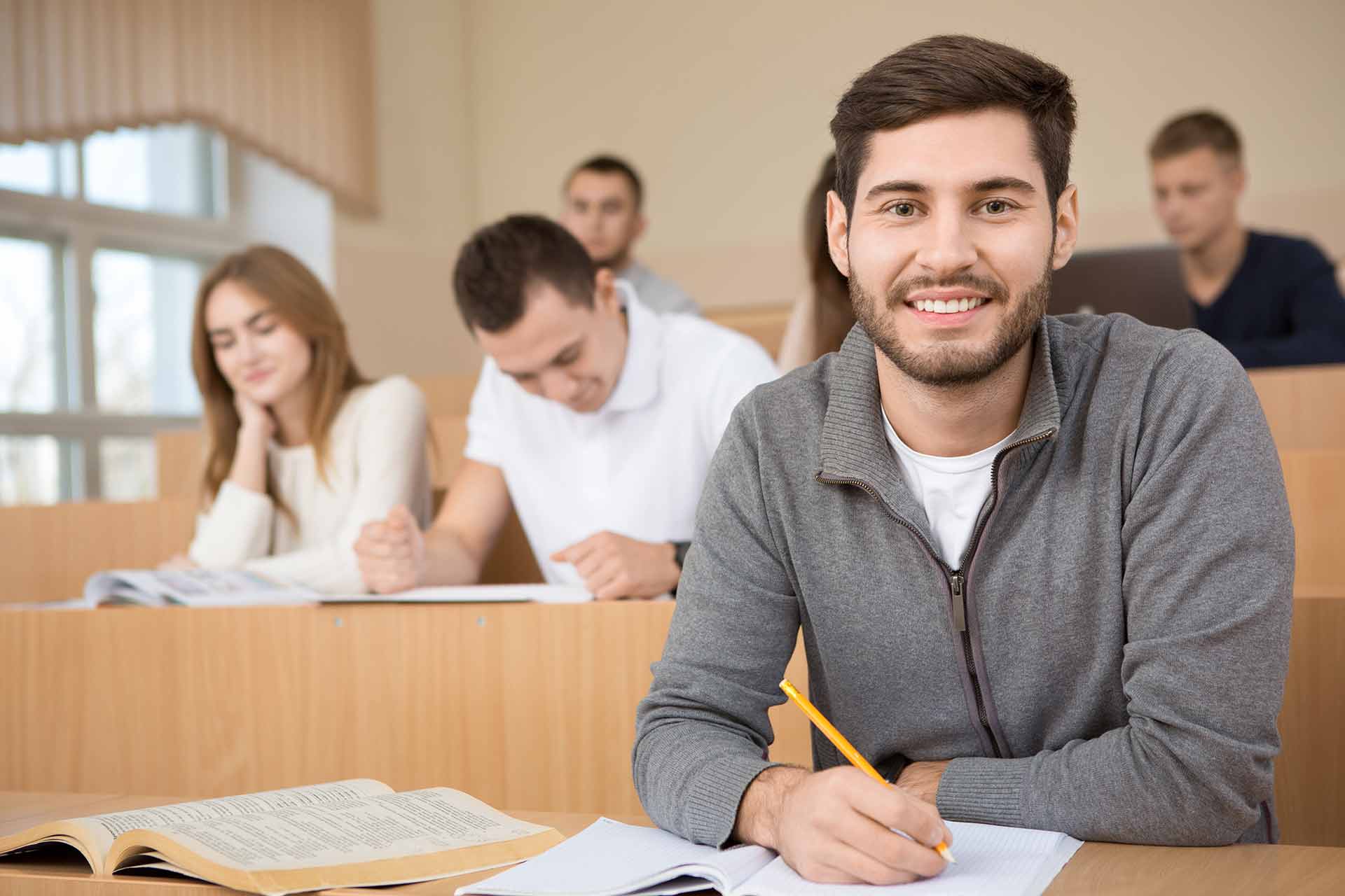 Un hombre joven estudiando junto a sus compañeros en la universidad.