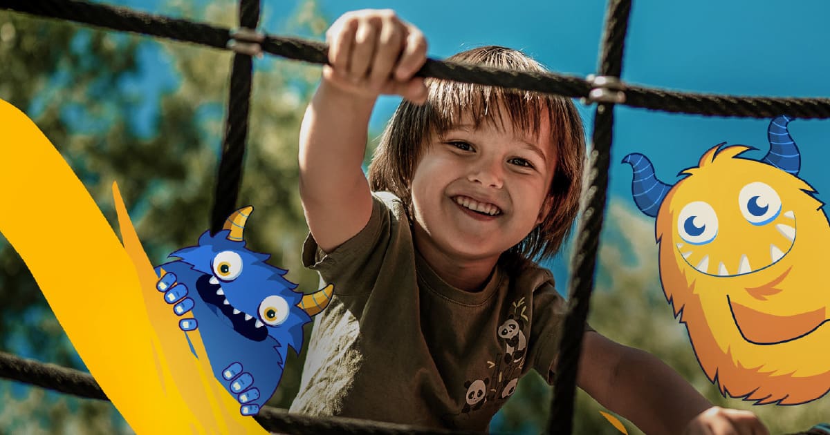 Un niño sonriente escalando con unas cuerdas en los colegios Colsubsidio.