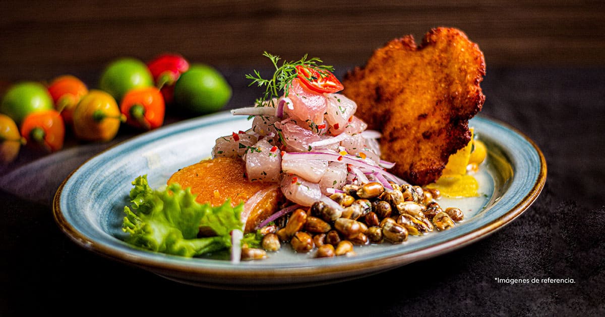 Un plato peruano con maíz, lechuga, guarnición y de fondo unos pimentones, preparado en el Café de las Letras. 